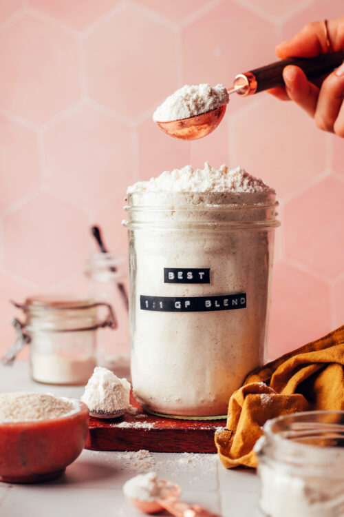 Picking up a spoonful of gluten-free flour blend from a jar