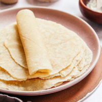 Rolled cassava flour tortilla on a plate on top of a stack of more tortillas