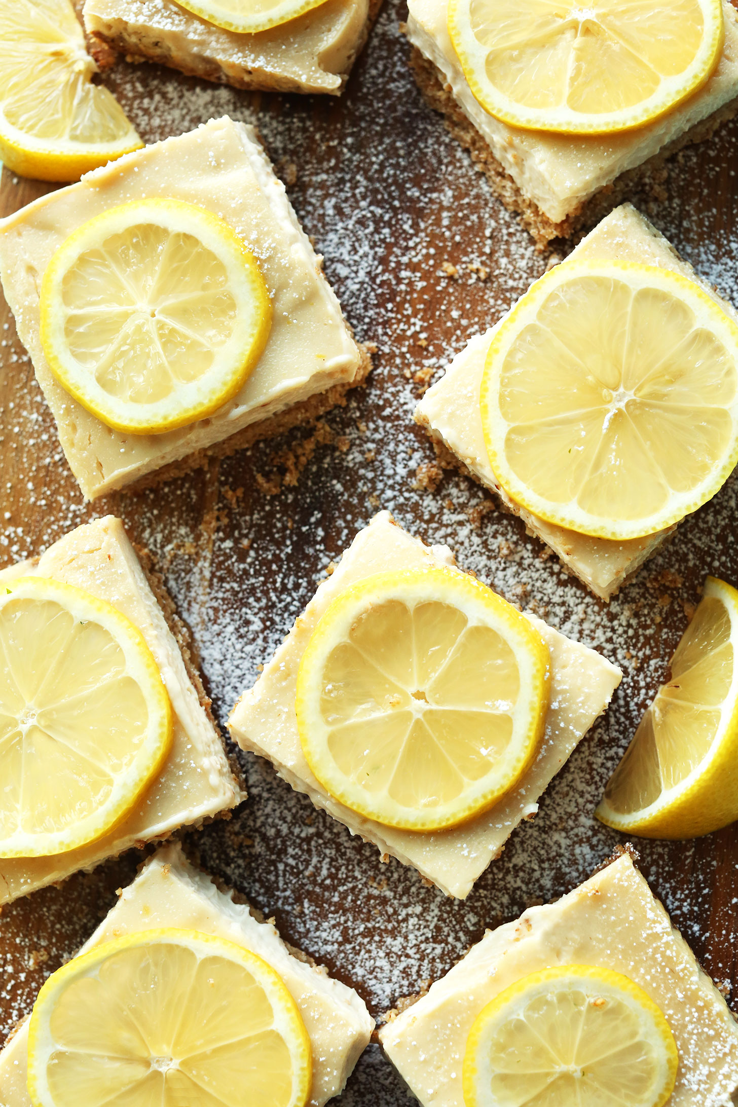 Squares of delicious homemade vegan gluten-free lemon bars on a wood board