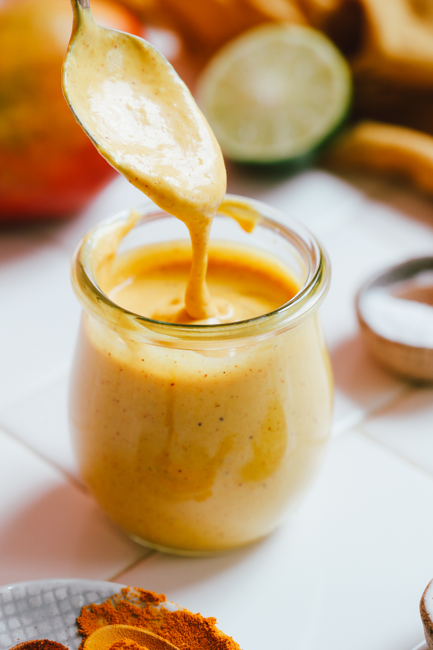Creamy mango vinaigrette salad dressing dripping from a spoon into a jar