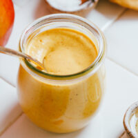 Spoon in a small Weck jar of creamy turmeric mango vinaigrette