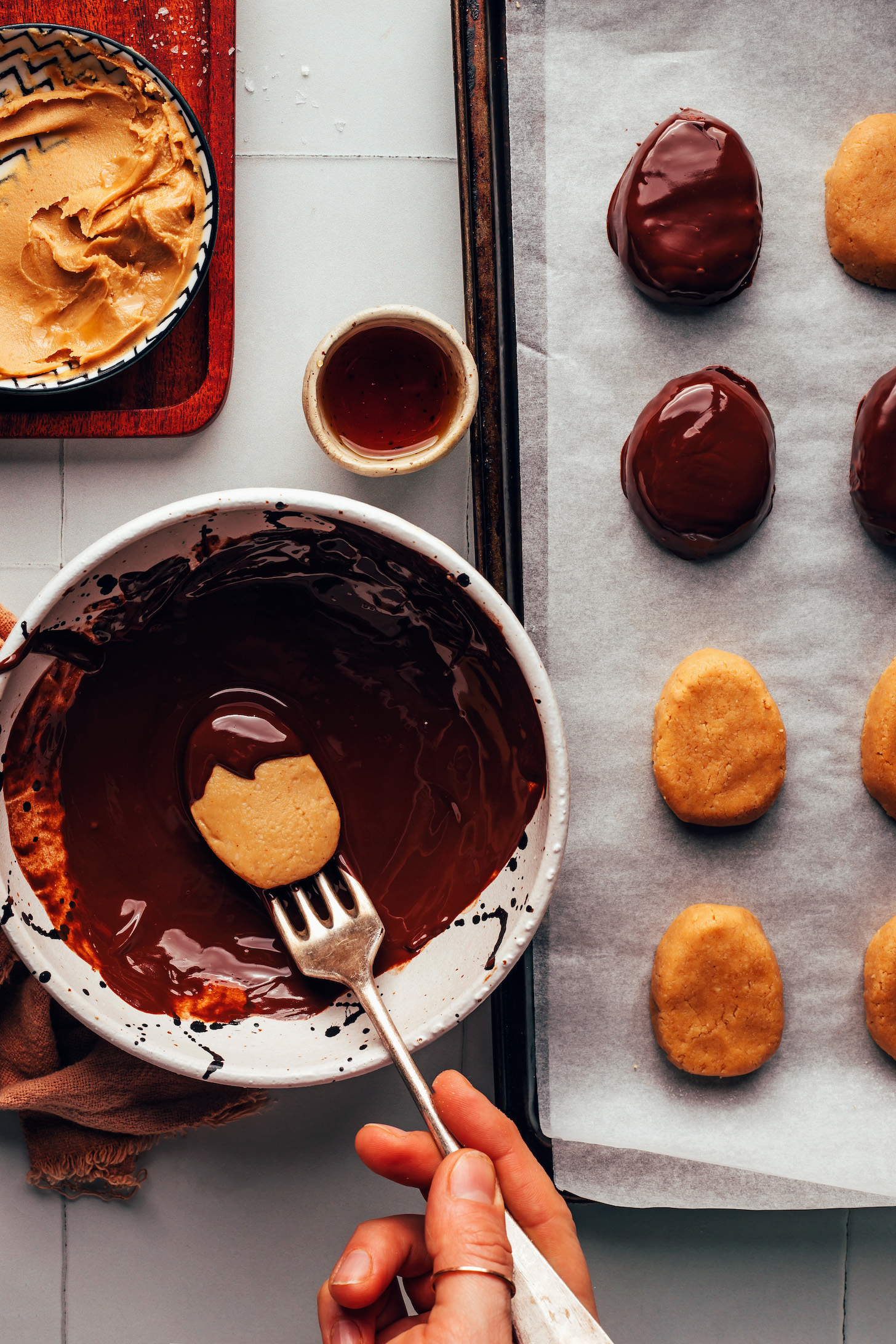 Dipping an oval-shaped peanut butter  mixture into a bowl of melted chocolate
