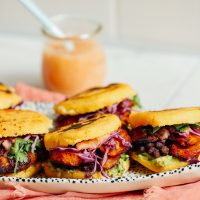 Tray of Vegan Arepa Sandwiches with Plantains, Black Beans, Guacamole, and a jar of habanero hot sauce