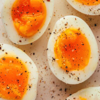 Close up shot of jammy eggs sprinkled with salt and black pepper