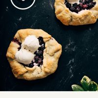 Two mini Blueberry Galettes with scoops of ice cream on a dark background