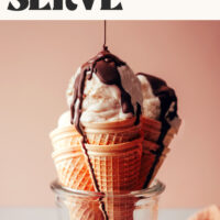 Cones of vegan vanilla soft serve with chocolate being drizzled on top