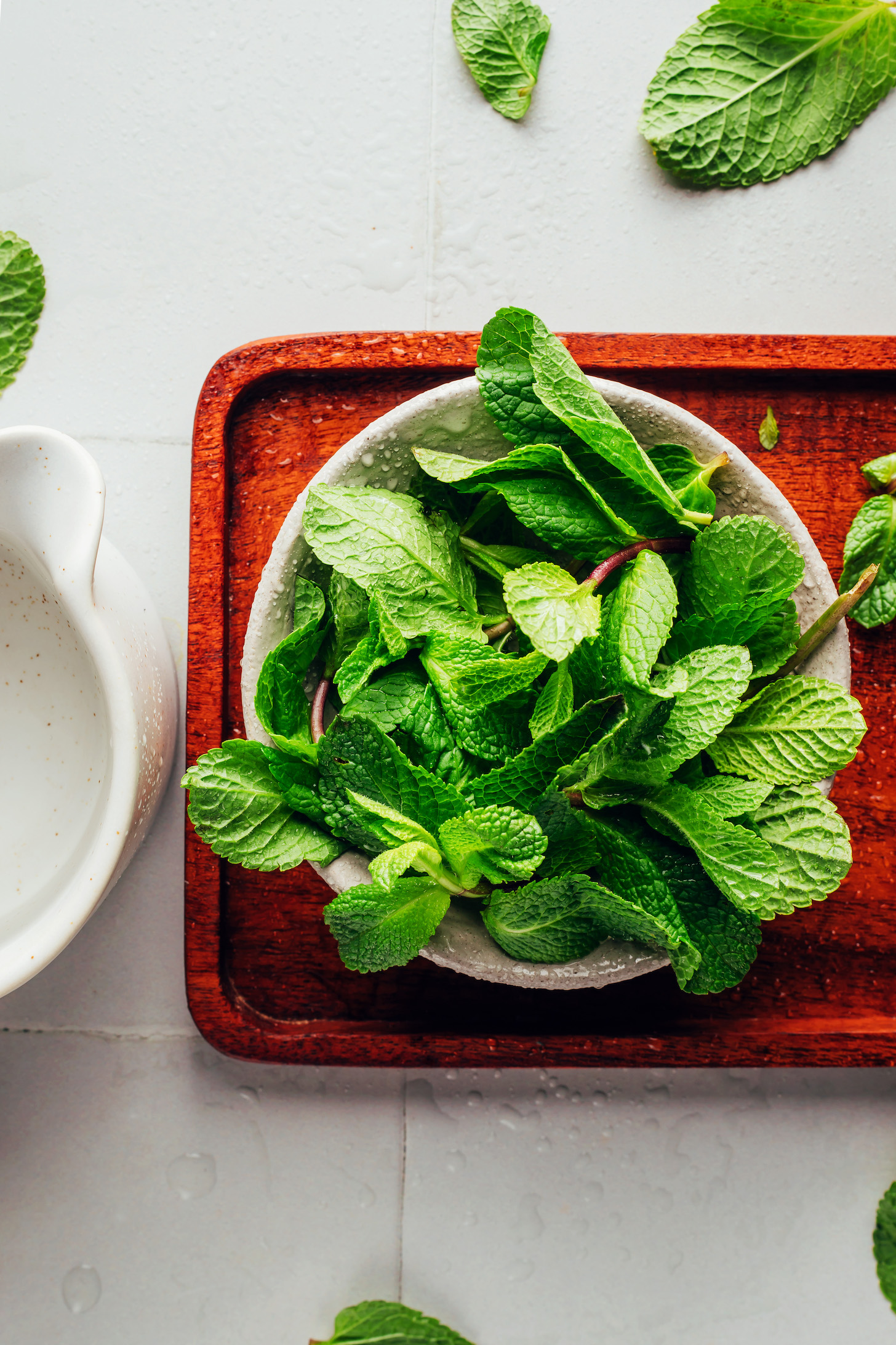 Bowl of water next to a bowl of fresh spearmint leaves