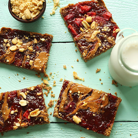 Peanut Butter and Jelly Snack Bars beside dairy-free milk and a bowl of peanuts
