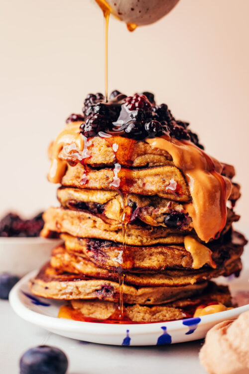 Drizzling maple syrup onto a stack of plantain pancakes