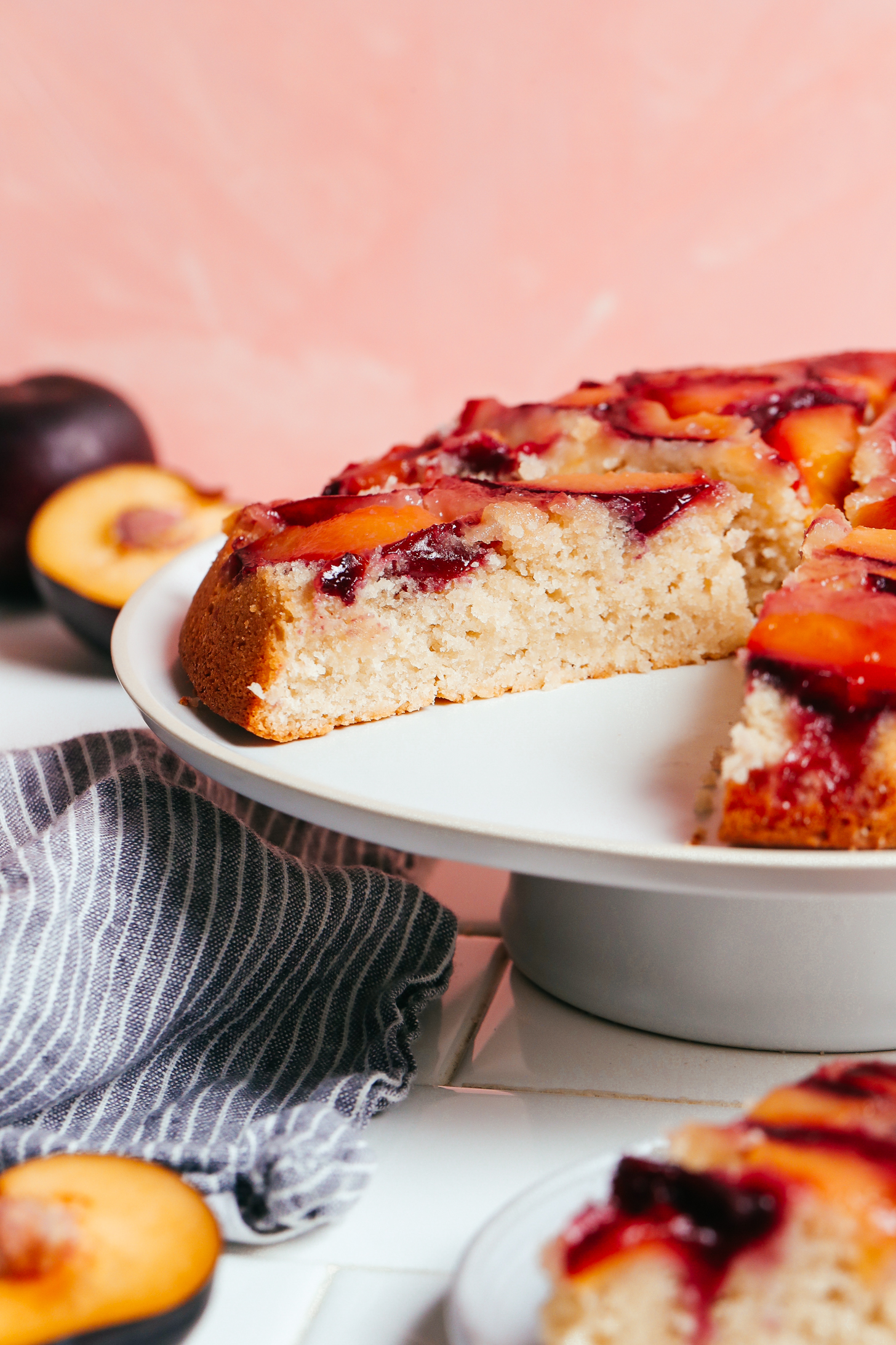 Side view of a partially sliced plum upside down cake on a platter