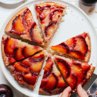 Removing a slice of plum upside down cake from a plate
