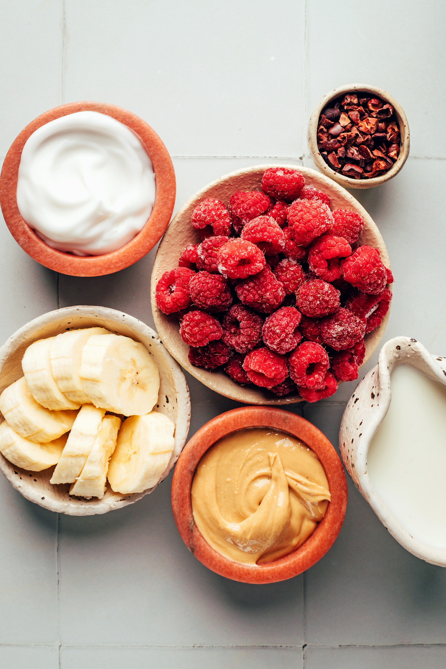 Dairy-free yogurt, banana, cashew butter, dairy-free milk, raspberries, and cacao nibs