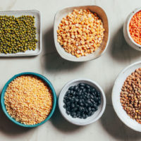 Assortment of dried legumes including mung beans, chickpeas, moong dal, black bean, chana dal, red lentils, and green lentils