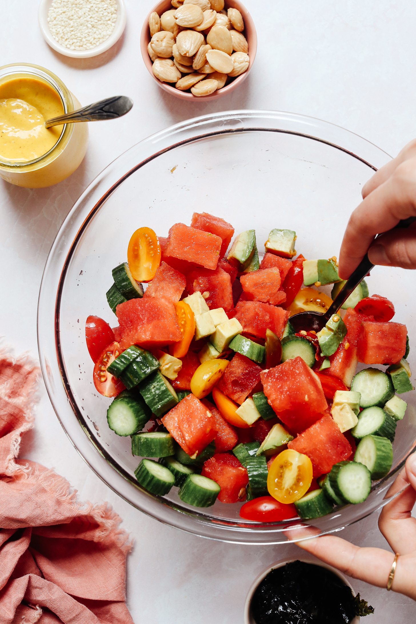Stirring together cubed watermelon, mango, avocado, and tomato in a mixing bowl