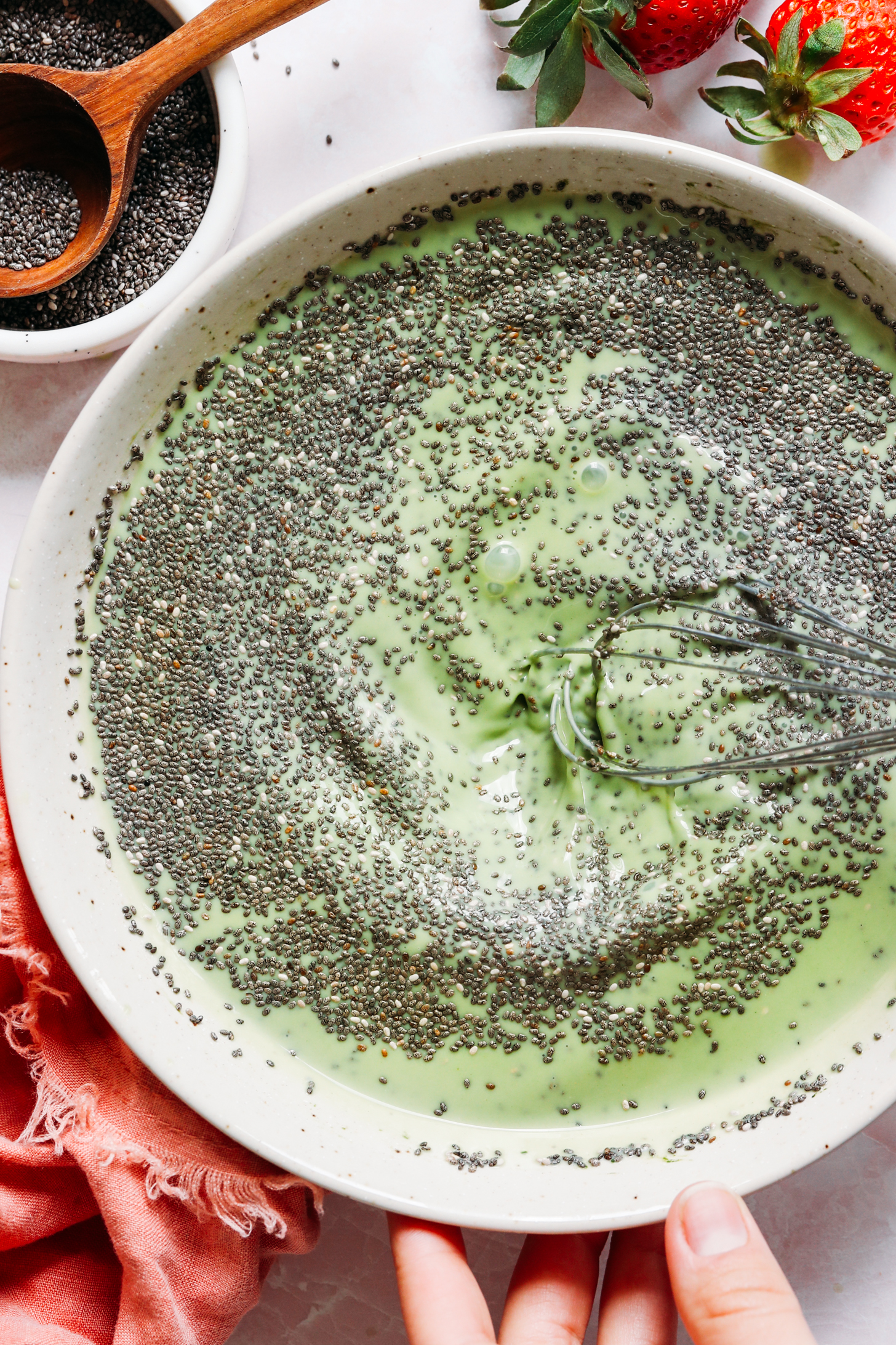 Whisking chia seeds into a vibrant green matcha mixture