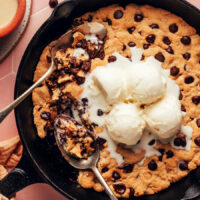 Overhead shot of a tahini chocolate chip skillet cookie topped with scoops of vanilla ice cream