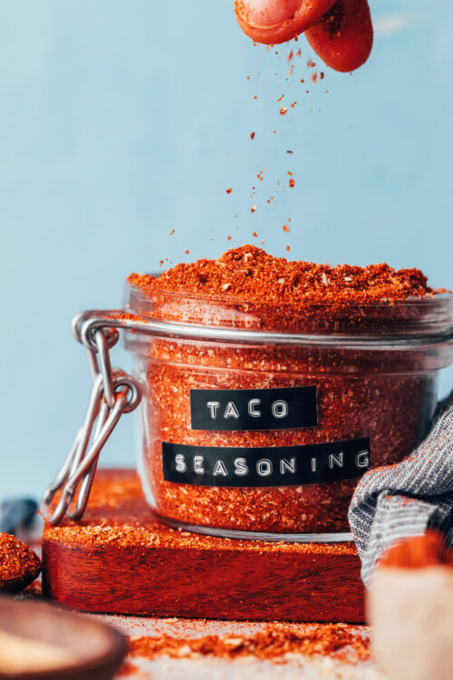 Sprinkling taco seasoning into a glass jar