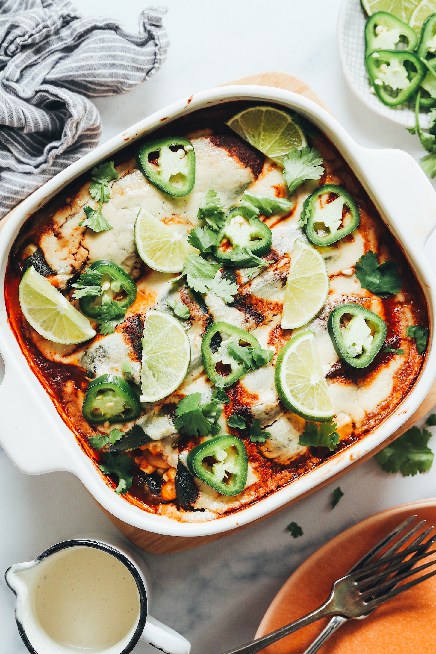 Baked vegan chile relleno in a pan topped with jalapeño, cilantro, and limes