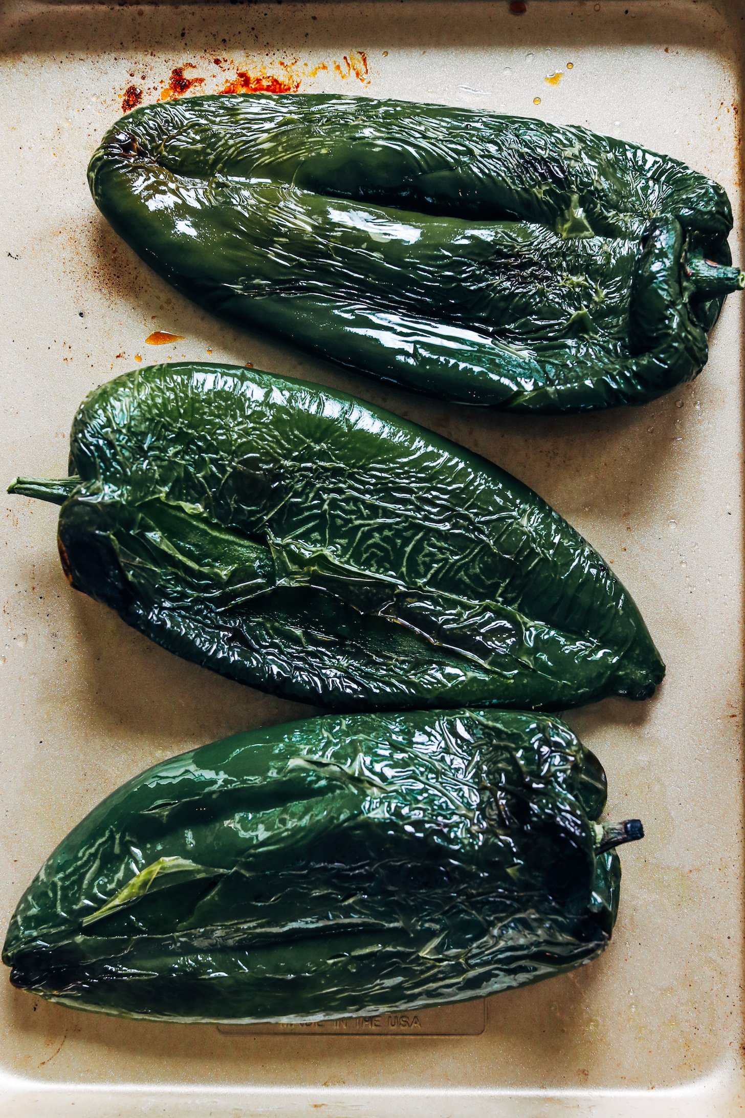 Blistered poblano peppers on a baking sheet