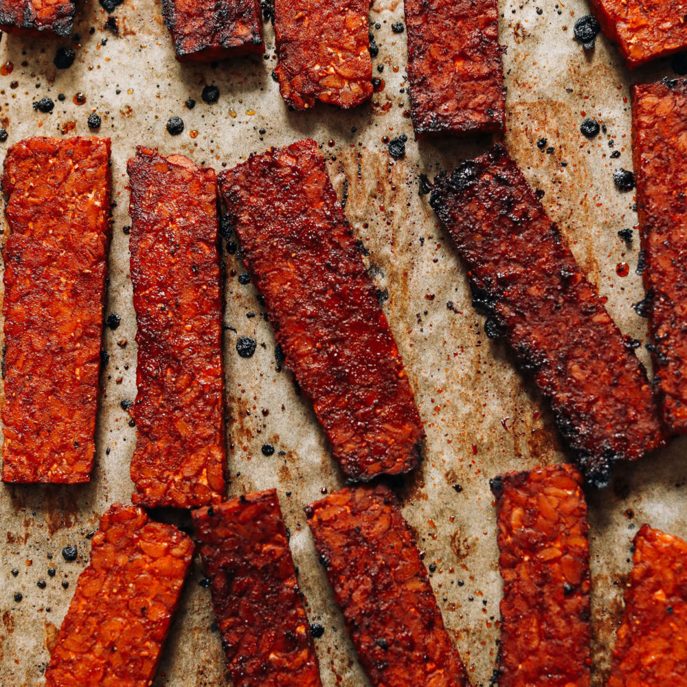Strips of crispy vegan tempeh bacon on a baking sheet